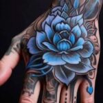 A large blue lotus flower tattoo intricately detailed on the back of a person's hand.