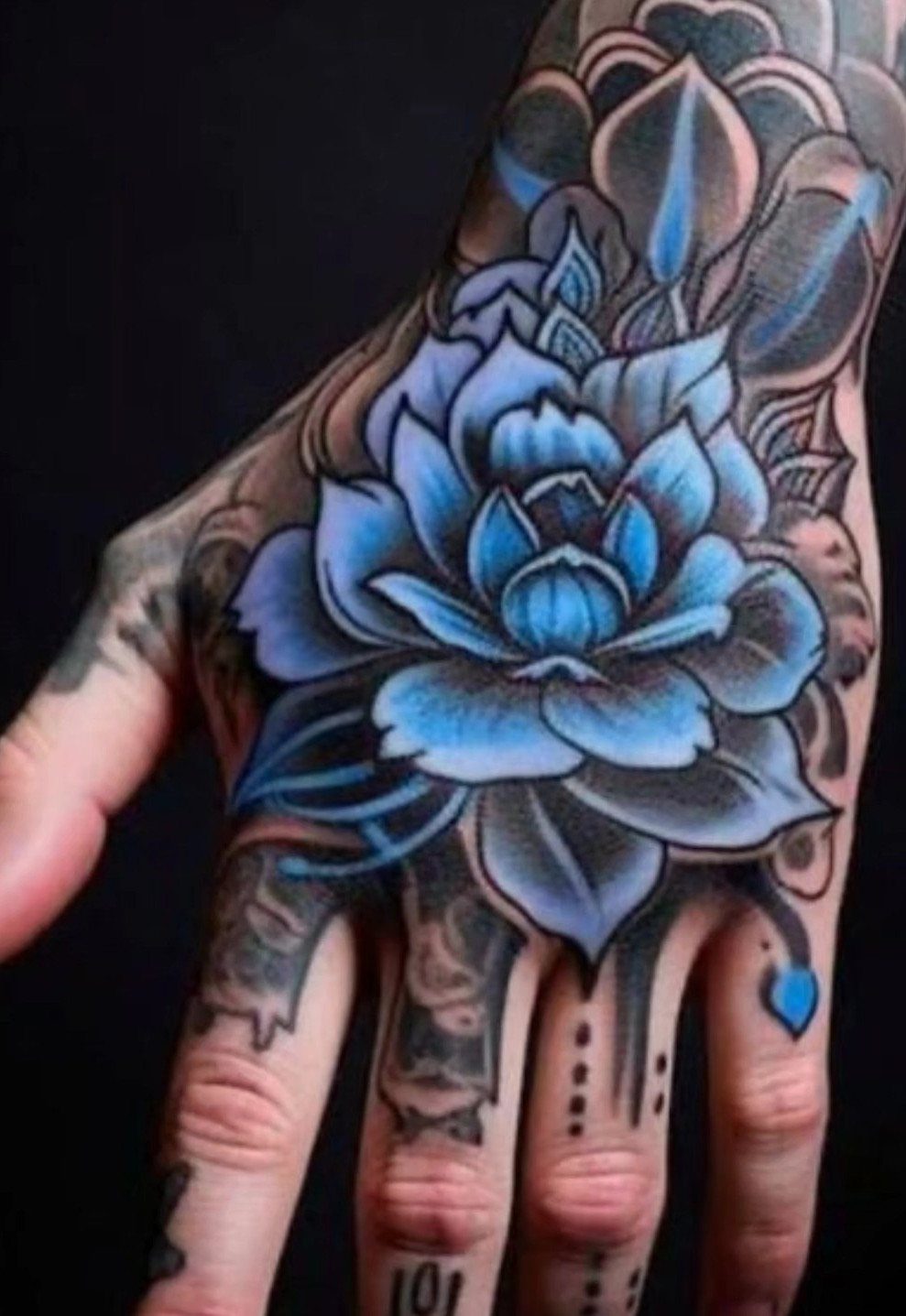 A large blue lotus flower tattoo intricately detailed on the back of a person's hand.