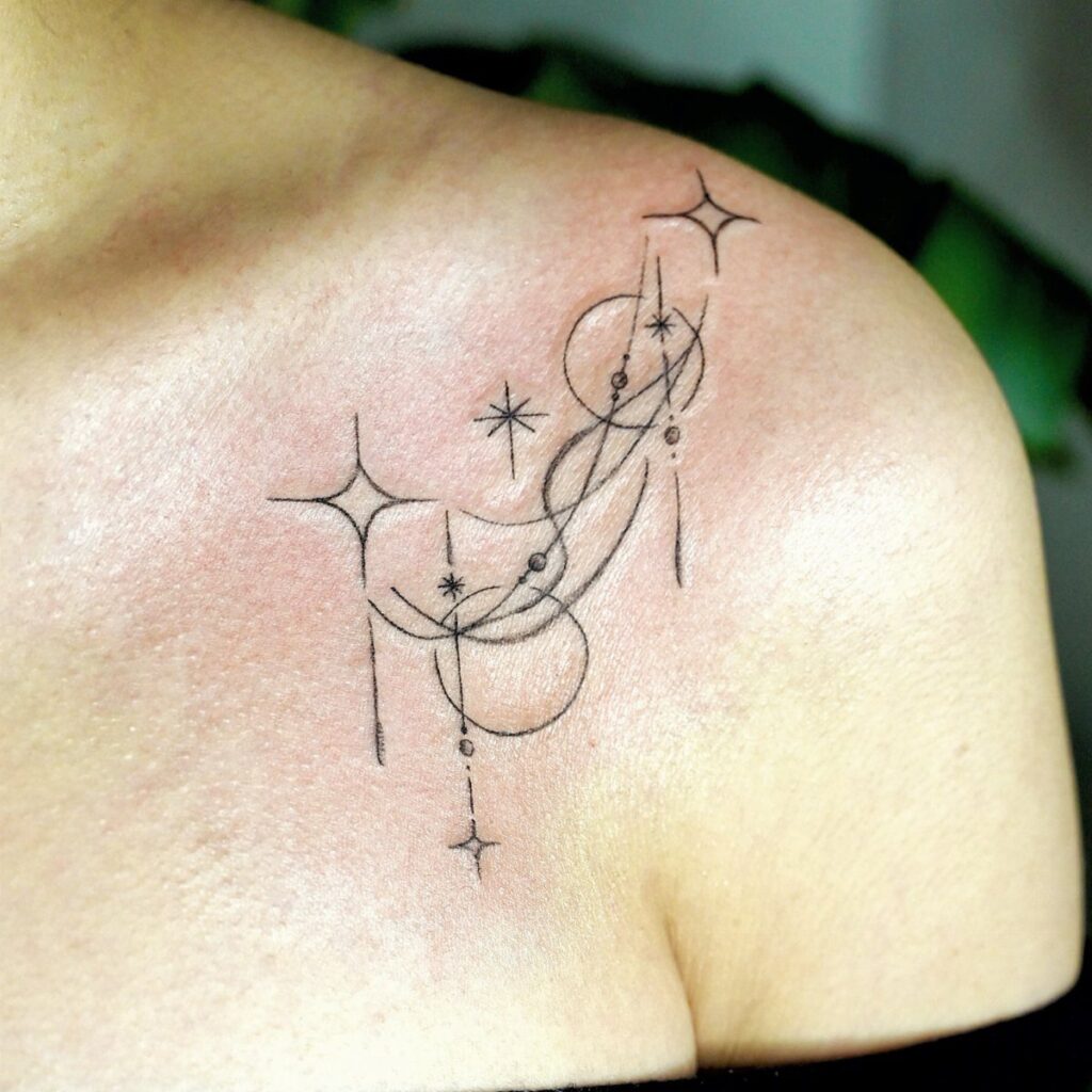 Fine line black ink tattoo with stars and geometric circles on a person's collarbone.