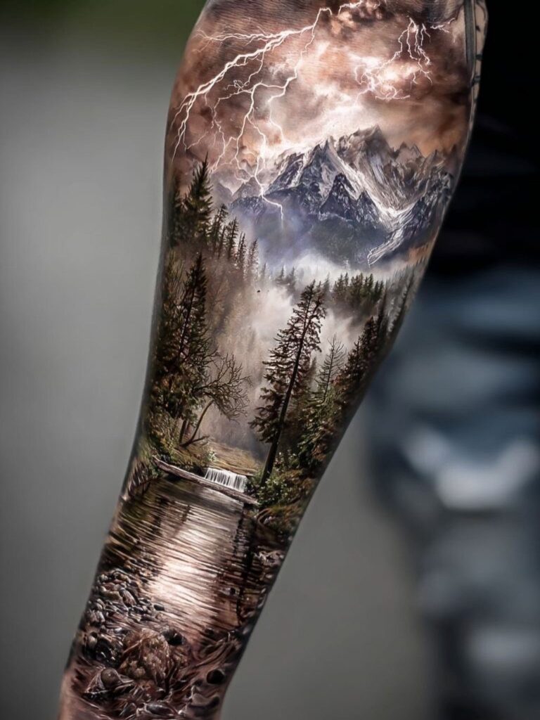 A detailed landscape tattoo on an arm showing mountains, forests, a waterfall, and lightning.