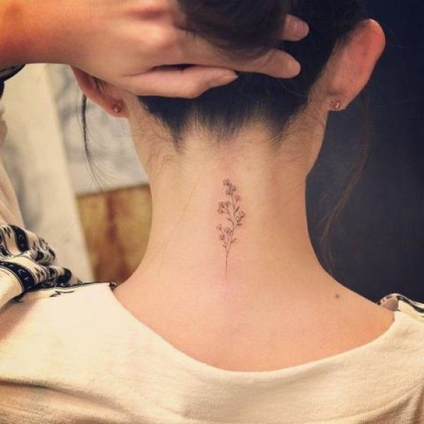 A delicate floral tattoo on the back of a woman's neck with fine line botanical details.