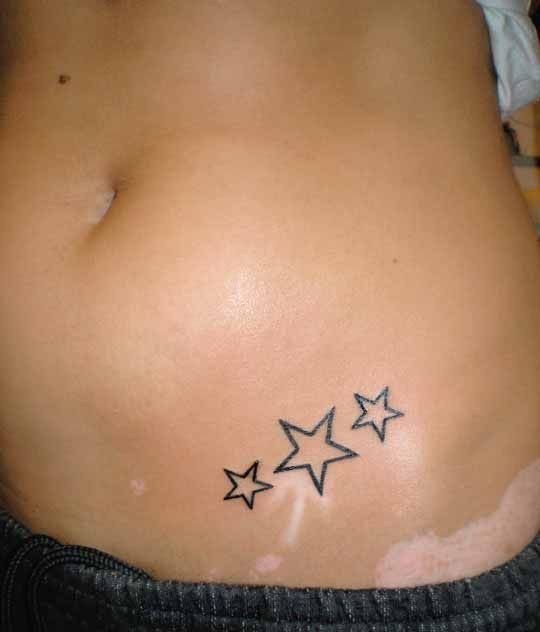 Three small black ink outline stars tattooed diagonally on a person's hip.