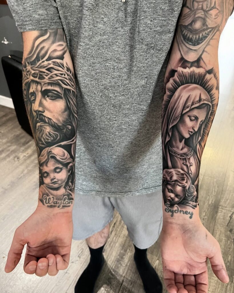 Two tattooed forearms displaying large black and grey religious portraits and names.